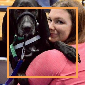 A photo of Rebekah looking over her shoulder and smiling at the camera while her black service dog Zoey rests on her shoulder.