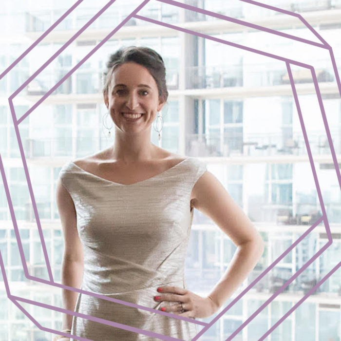 Kelly, a white woman wearing a white dress, smiles at the camera. There is a stylized purple hexagon framing the photo.