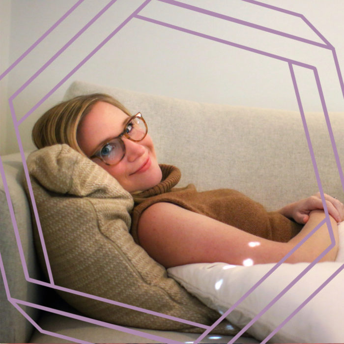 a photo of Natasha reclined on the couch, smiling at the camera. There is a stylized purple hexagon framing the photo.
