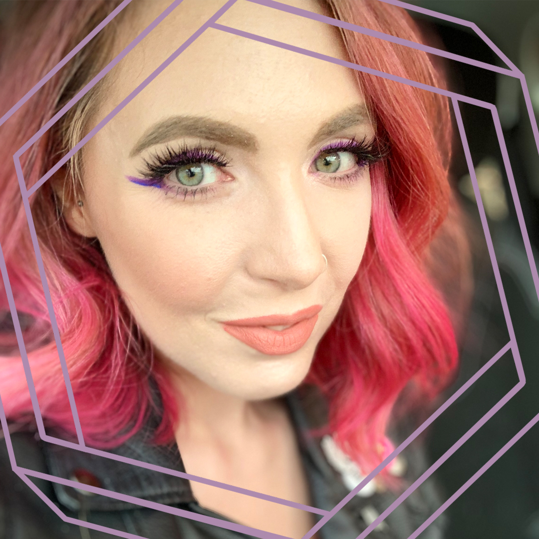 Emma, a white woman with curled pink hair, smiles at the camera. There is a stylized purple octagon superimposed over the photo.