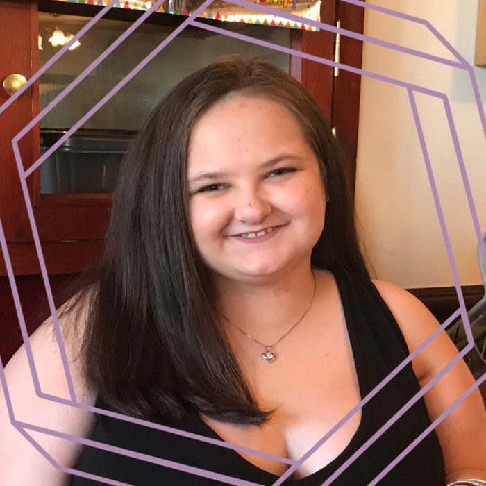 Niamh, an 18-year-old white woman with long brown hair, smiles at the camera.