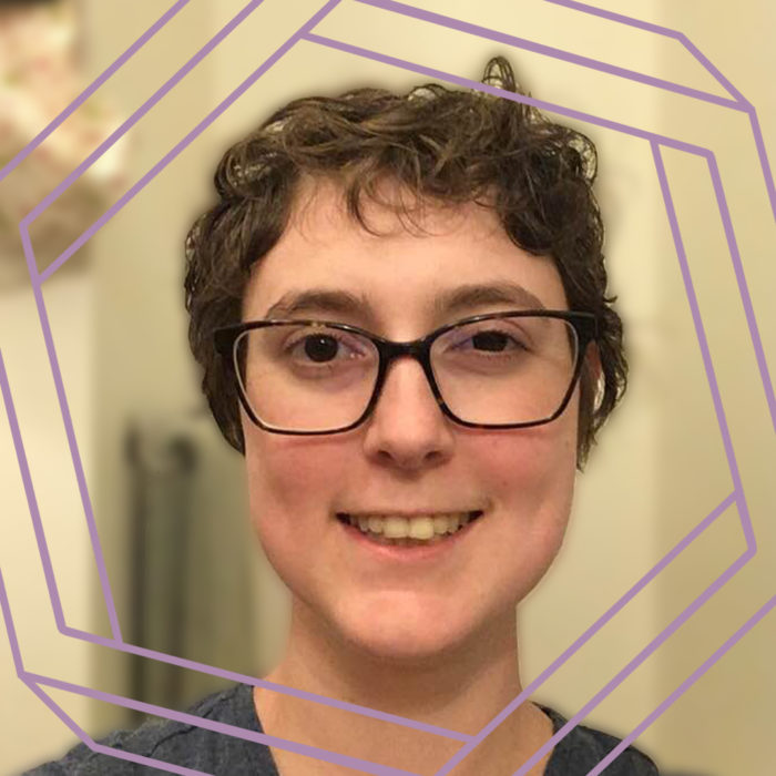 Nora, a white woman with black-framed glasses and short curly brown hair smiles at the camera. There is a stylized purple hexagon framing the photo.