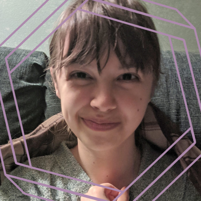 Hannah, a young white woman with bangs and dark brown hair pulled back into a ponytail, smiles at the camera. There is a stylized purple hexagon framing the photo.
