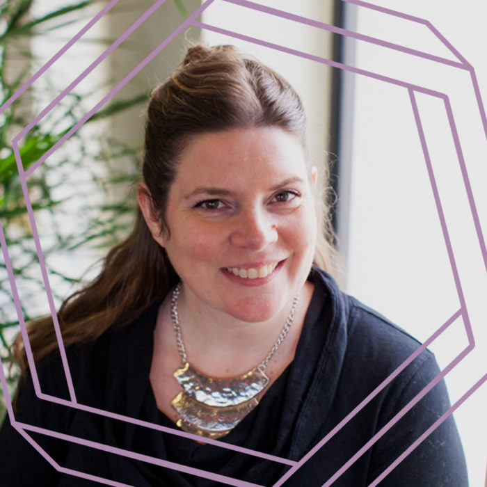 Alicia, a white woman with long brown hair, smiles at the camera. There is a stylized purple hexagon framing the photo.