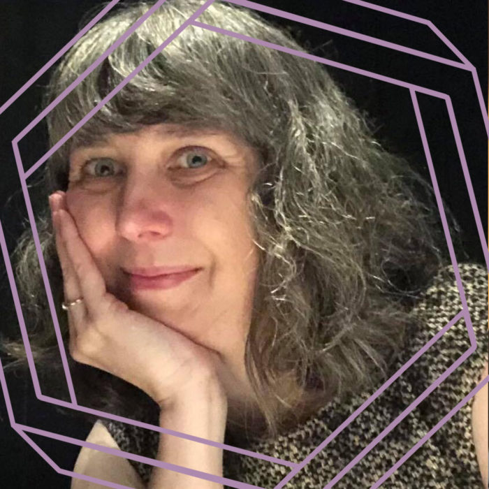 Michelle, a white woman with long grey hair, rests her chin on her hand and smiles at the camera. There is a stylized purple hexagon framing the photo.