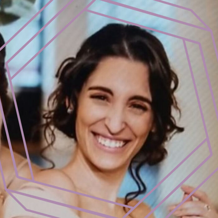 Adriana, a woman in her 20s with dark brown hair in a curled formal style, smiles at the camera. There is a stylized purple hexagon framing the photo.